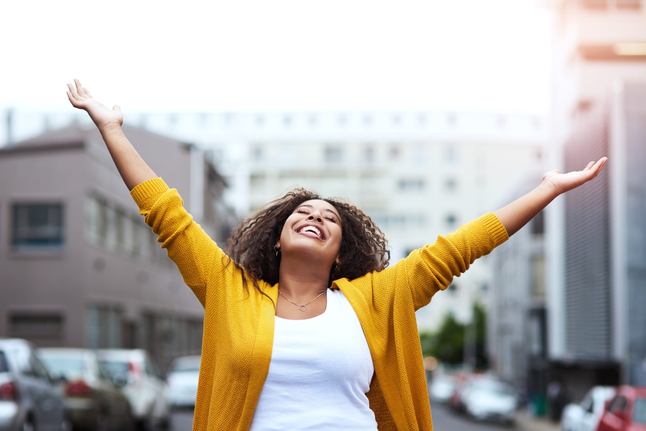 Woman smiling outdoors with her arms raised in joy